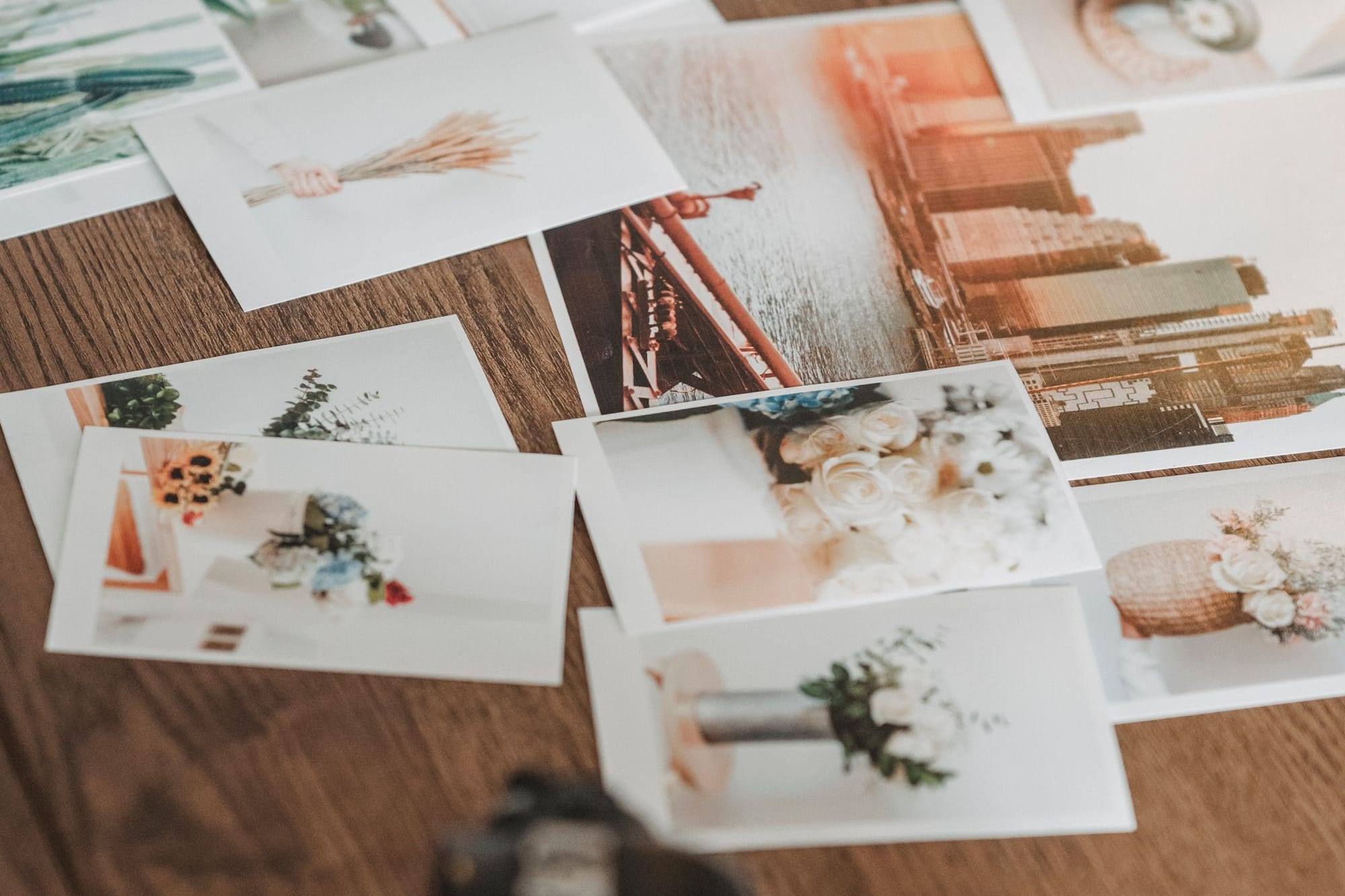 Fotos impresas de flores, interiores y una ciudad repartidas sobre una mesa de madera